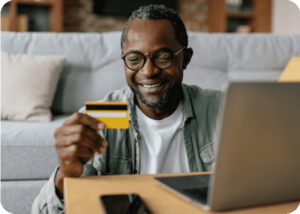 man looking at credit card while on laptop